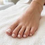 Sheer white jelly micro French toenails with gold anklet, sophisticated June toe nails ideas 2026.