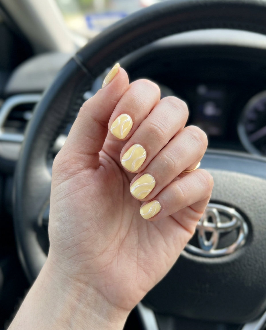 Short round summer nails 2026: Creamy butter yellow with pearlescent white abstract lines for elegant events.