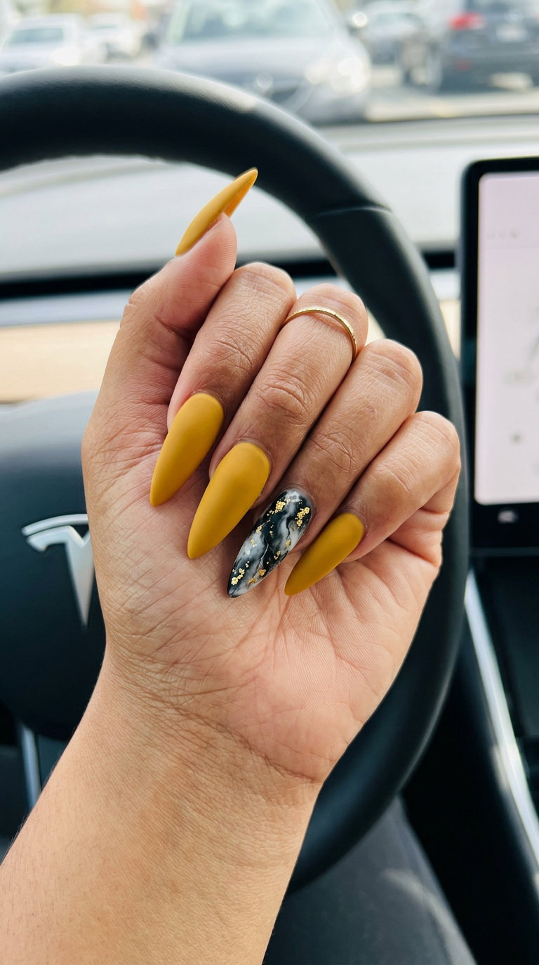 Mustard yellow summer nails 2026 with black and white marble accent and gold foil for an elegant evening out.