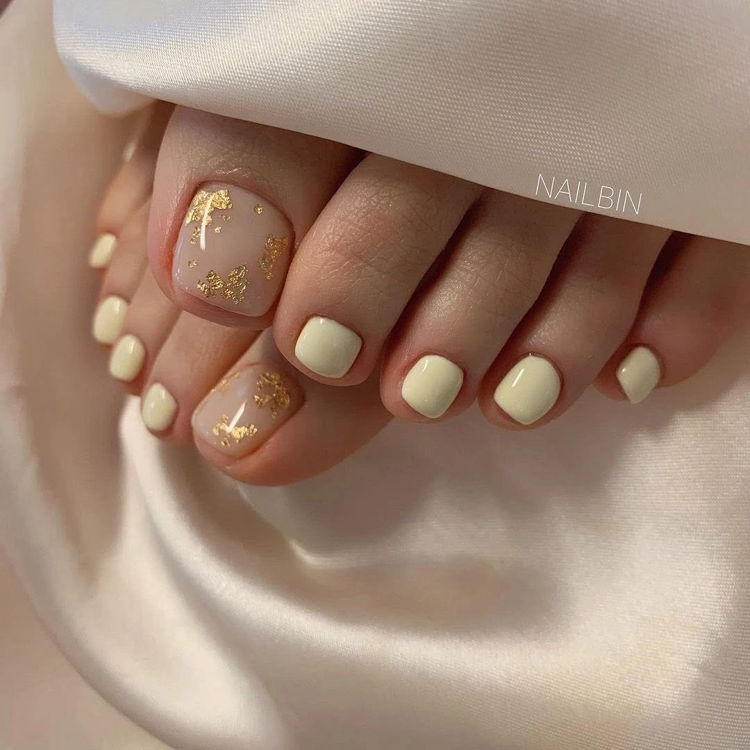 august pedicure nails ideas 2026 Soft Ivory Pedicure with Delicate Gold Leaf Accents