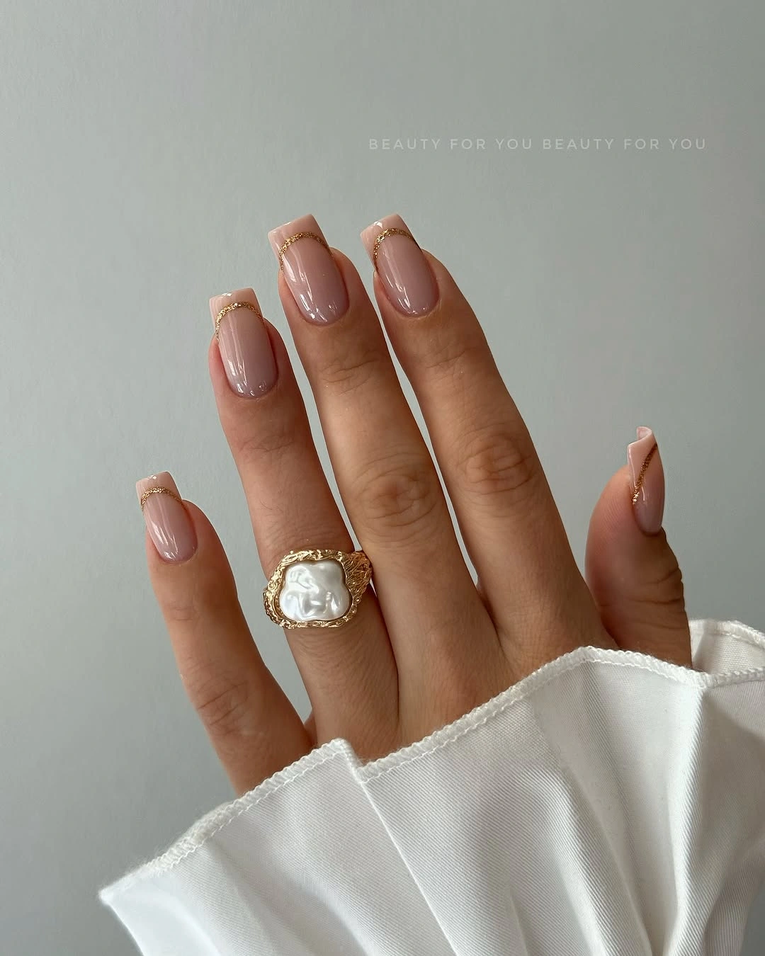 nude almond nails with gold French arcs