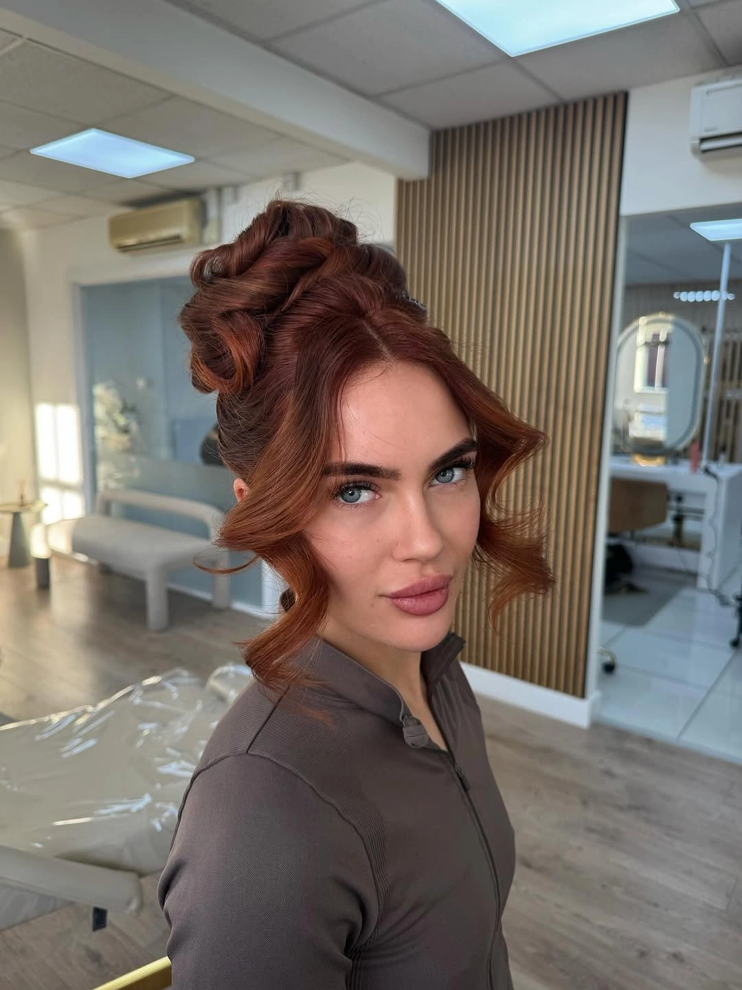 Fall hairstyles for wedding guests 2026 Soft Copper Updo with Romantic Face-Framing Pieces