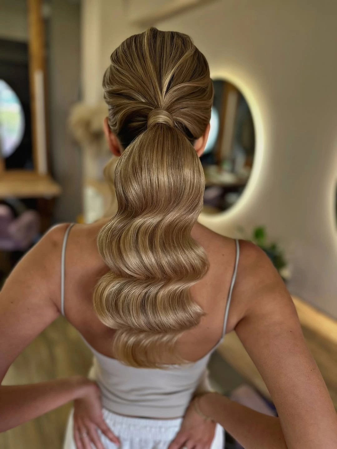 Fall hairstyles for wedding guests 2026 Sculpted Low Ponytail with Glossy Hollywood Waves