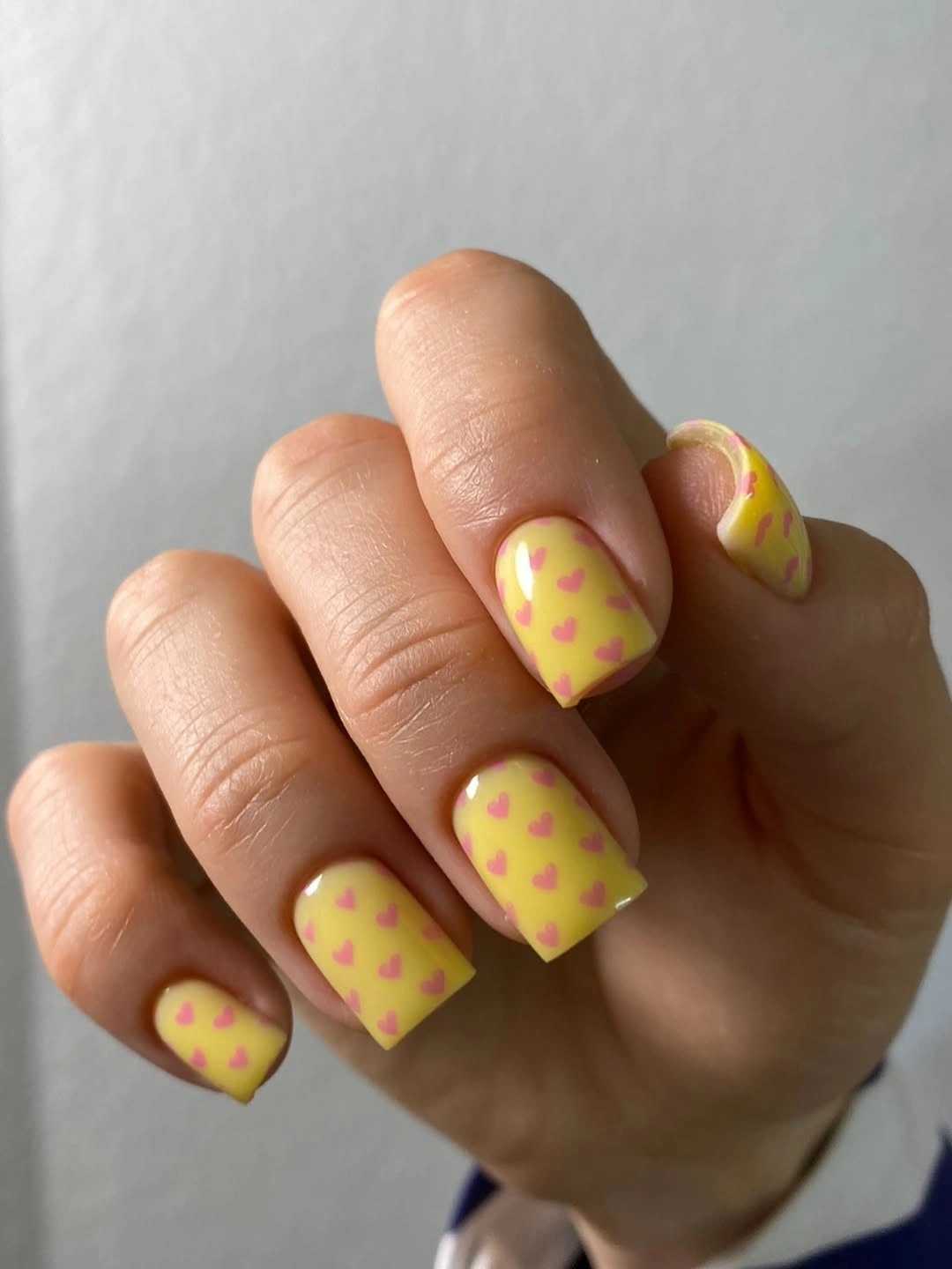 yellow square nails covered with tiny pink hearts
