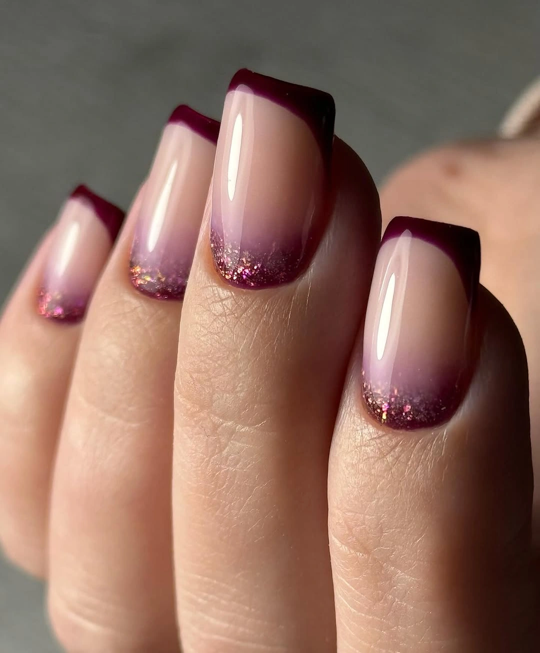 square nude nails with burgundy French tips and glitter base