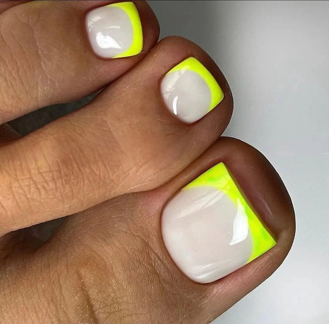 white pedicure with neon yellow curved French tips
