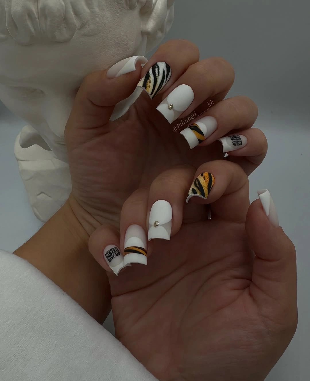 white square nails with black curved lines and gold accents