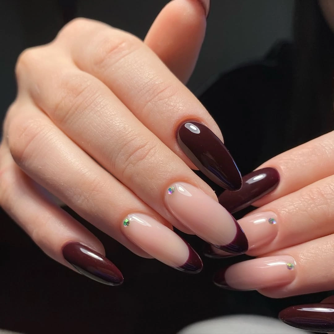 Nude almond nails with deep wine French tips and gold detail