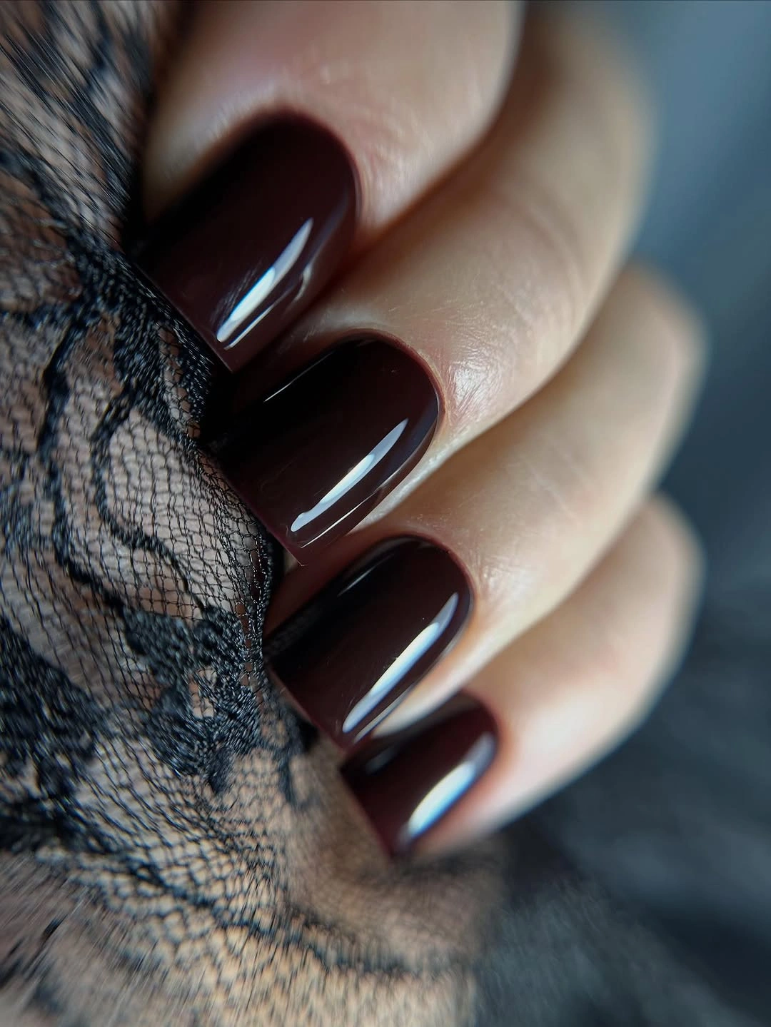 Long glossy black cherry almond nails beside black lace