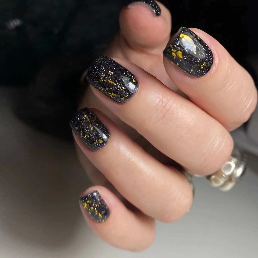 Short black nails with scattered multicolor reflective flecks