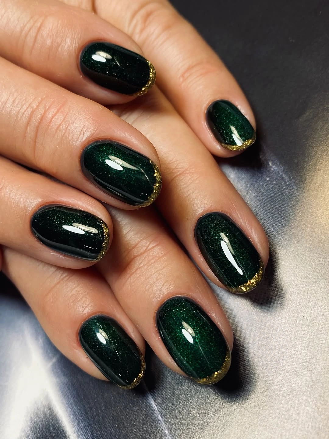Short forest green nails with thin gold-like edge accents