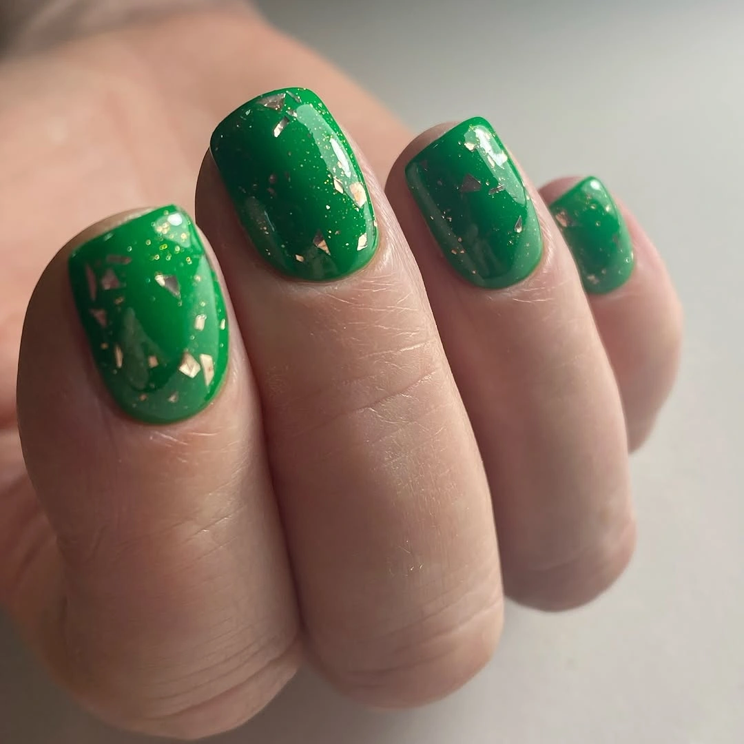 Short emerald green nails with scattered gold flecks