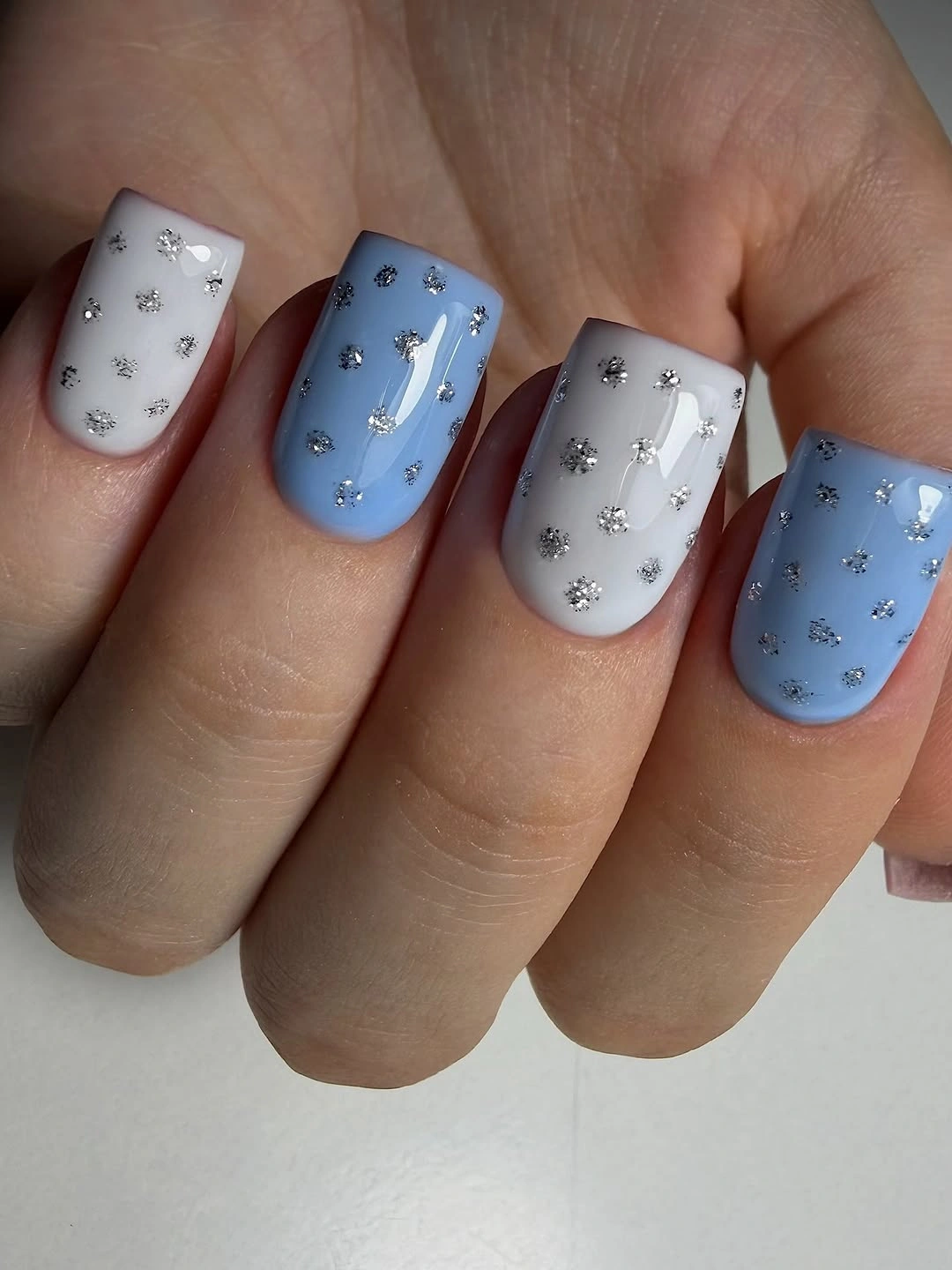 Long square milky white nails beside a neutral knit sleeve
