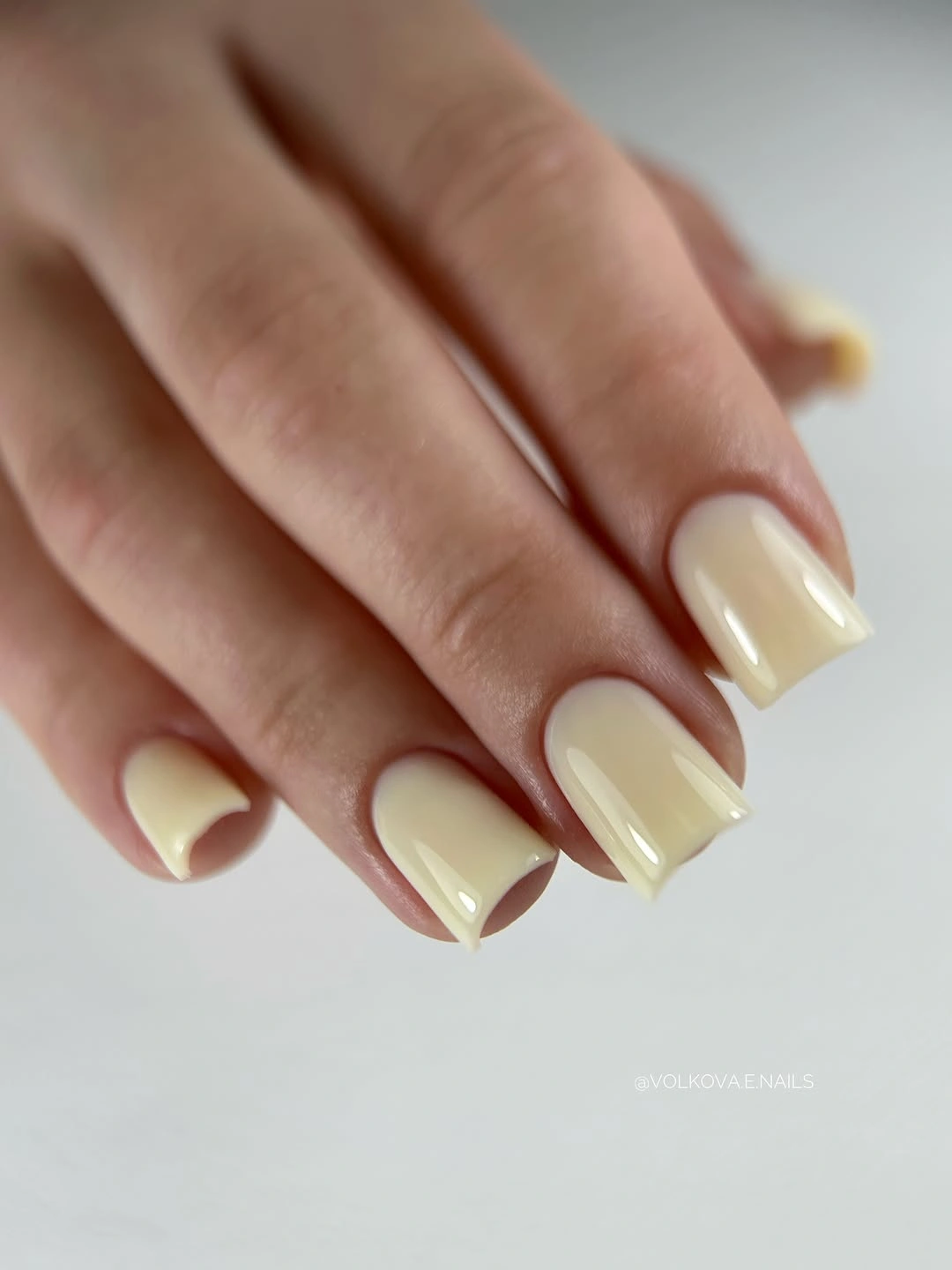 Short rounded-square nails in glossy pale buttery yellow