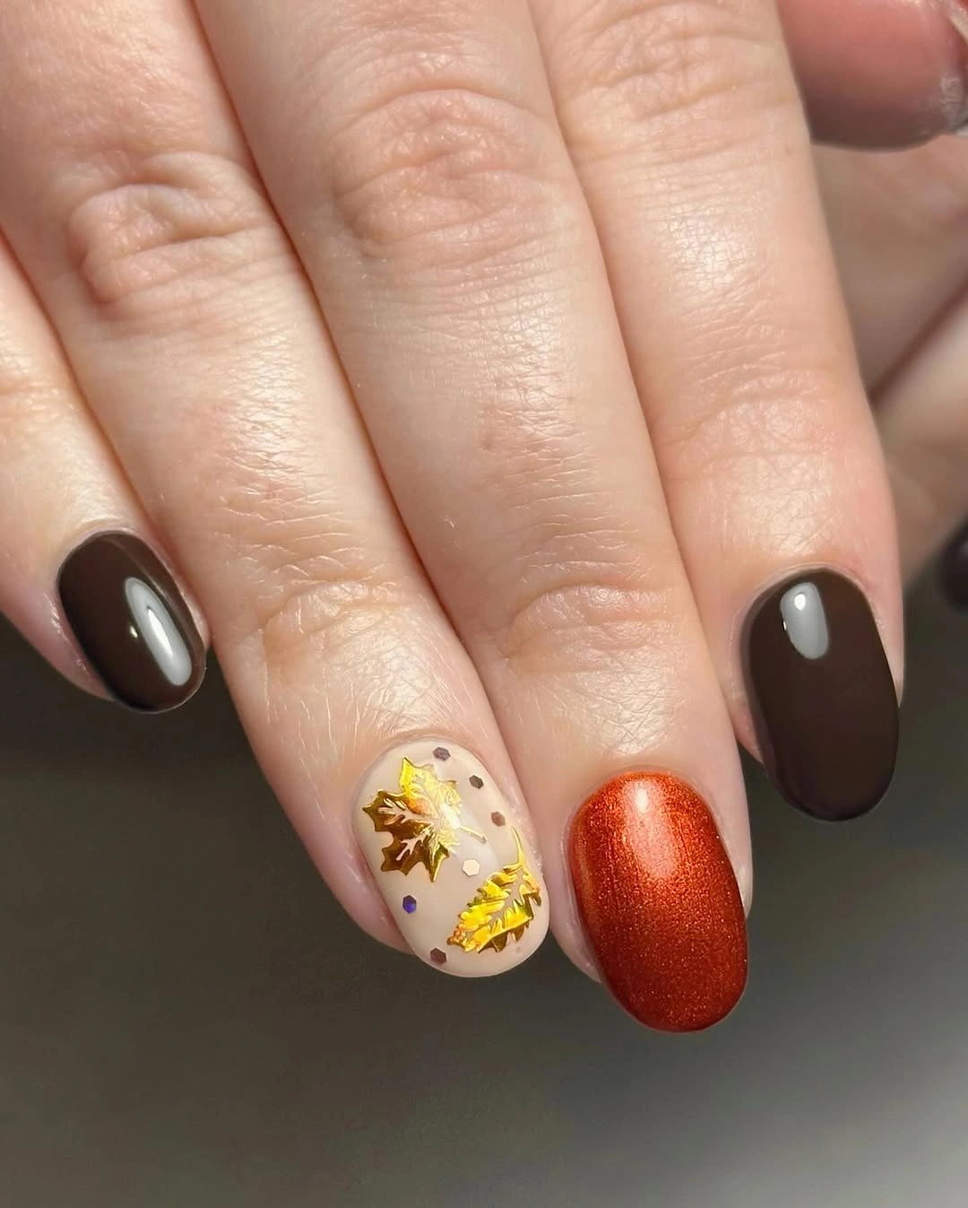 Brown nails with pale gold detail and orange metallic accent