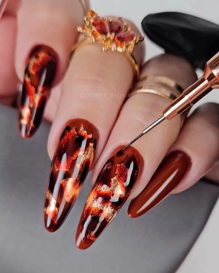 Burgundy almond nails with reflective copper abstract fragments