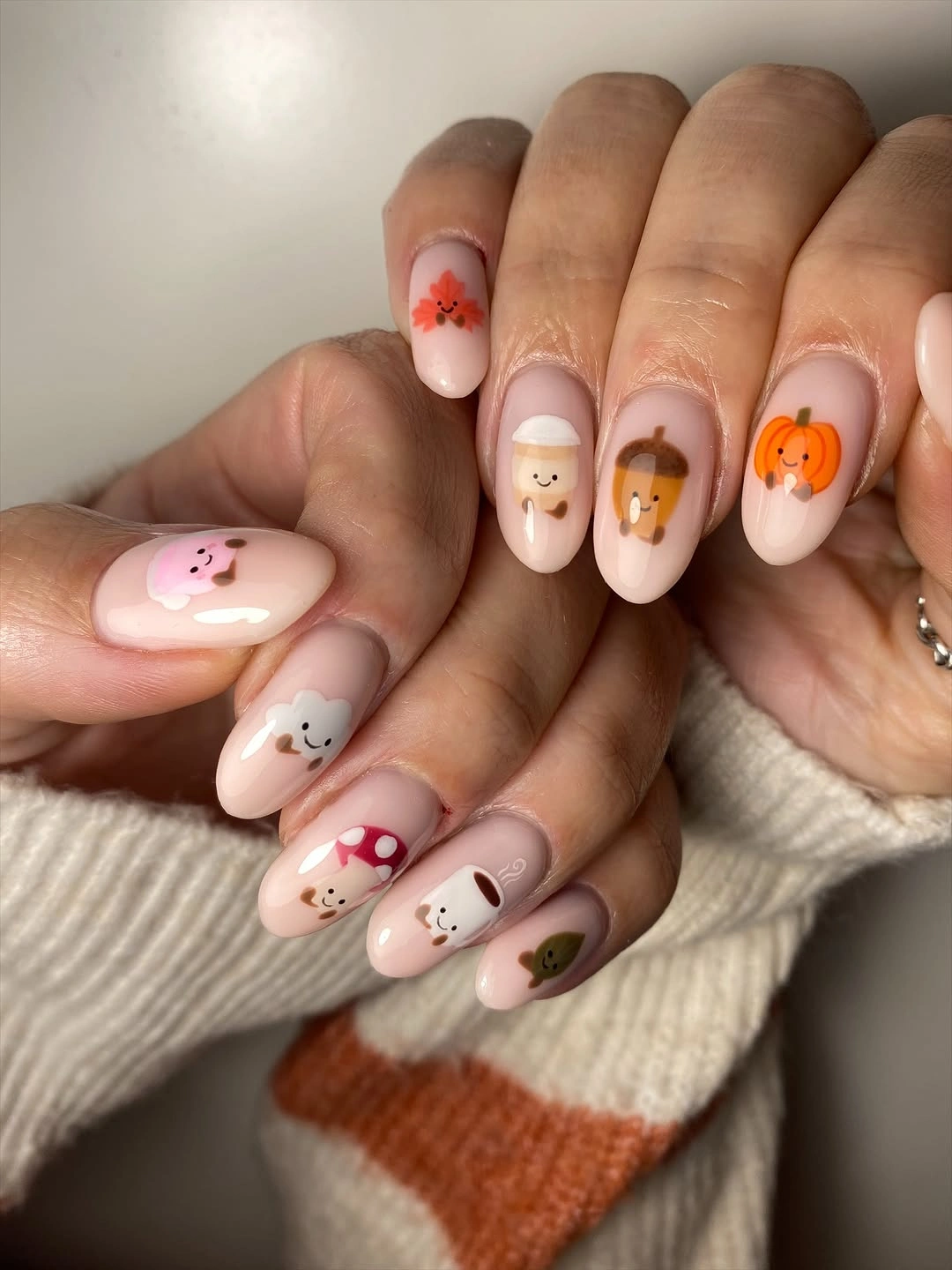Pale pink oval nails with tiny fall character accents