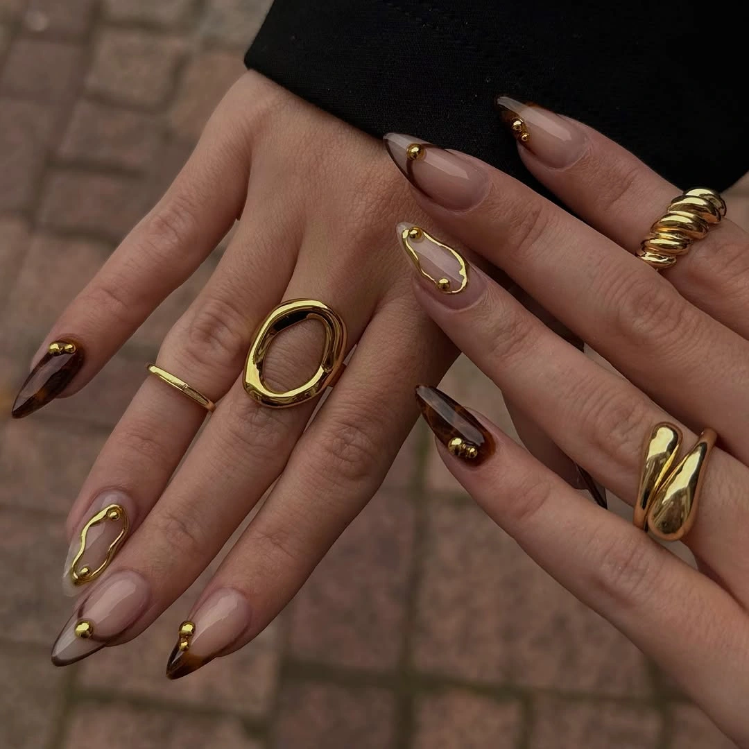 Pointed blush nails with smoky tips and gold loop accents