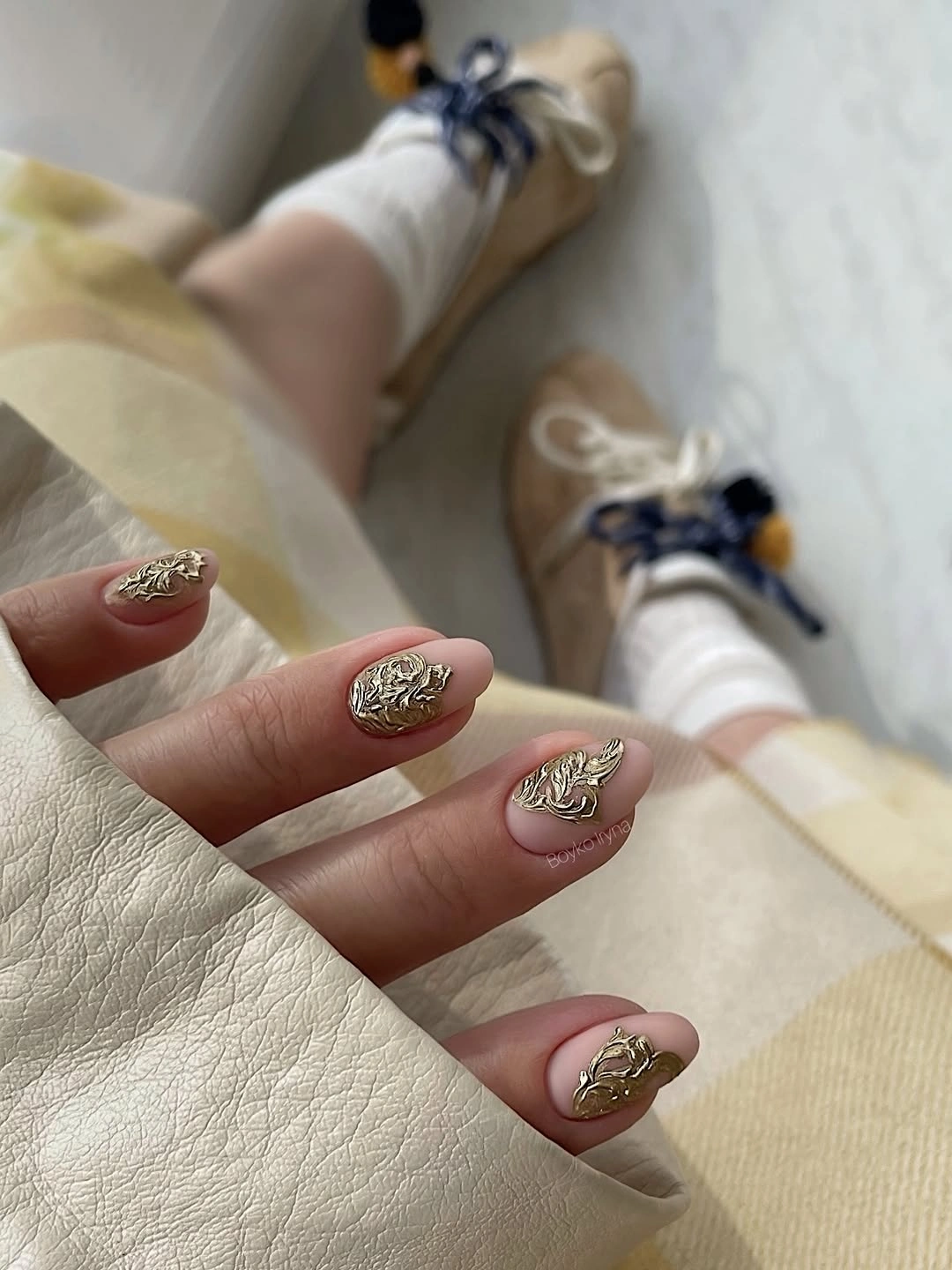 Short pale pink nails with ornate gold accent motifs