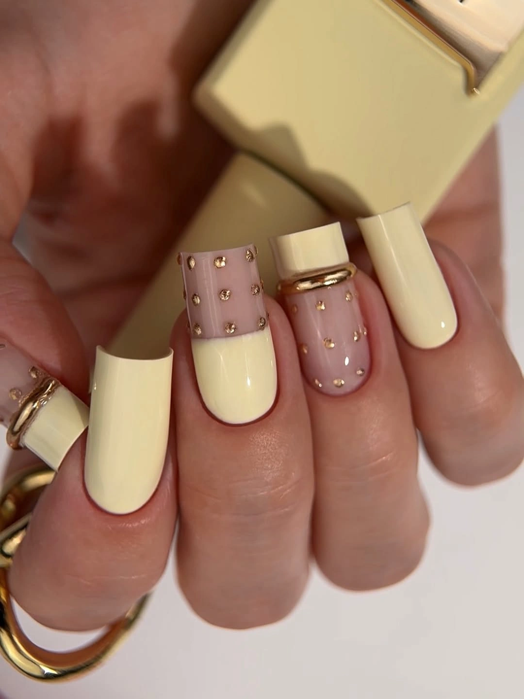 Pale yellow square nails with a blush studded accent