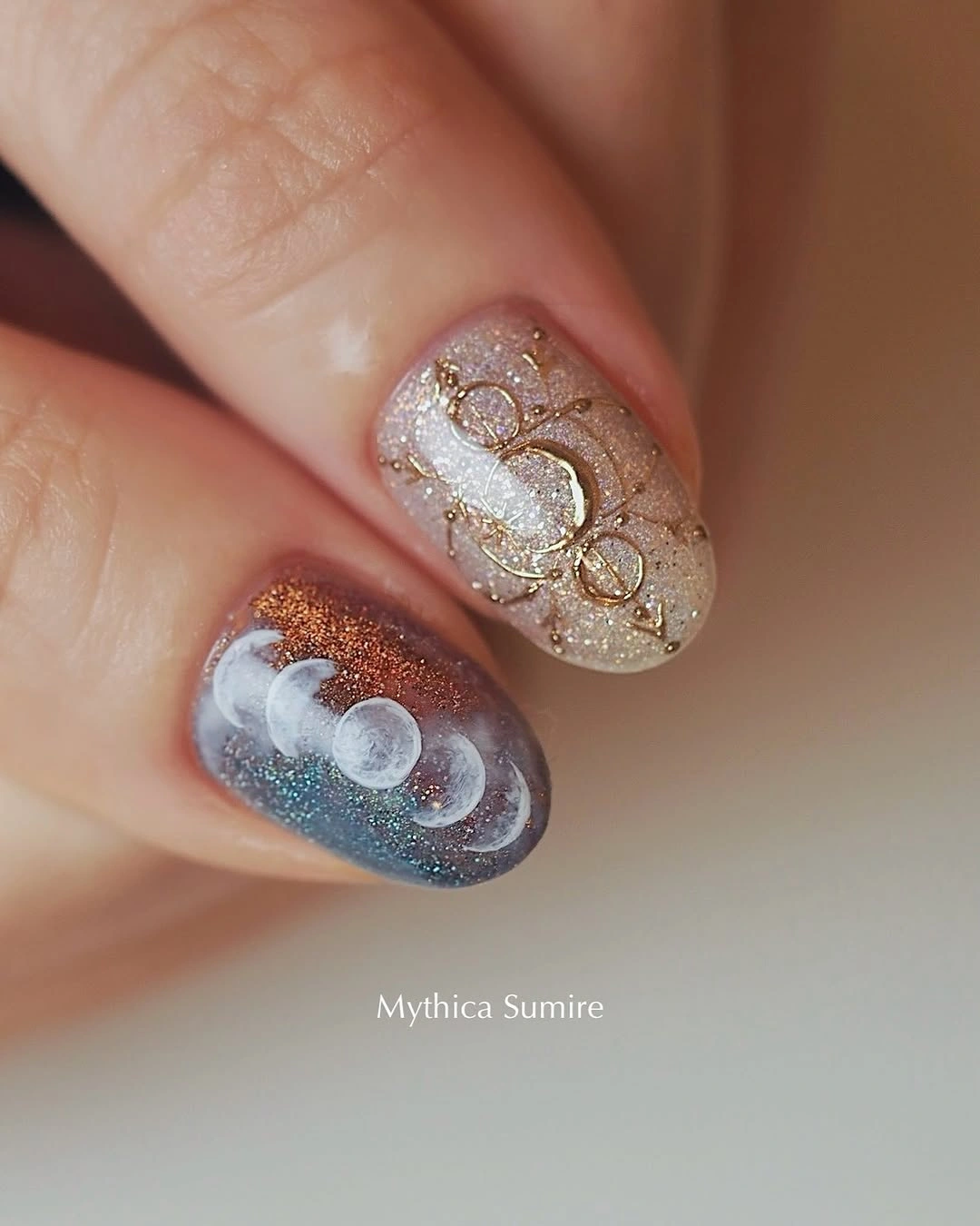 Glitter nails with pale gold loops and one cool blue accent