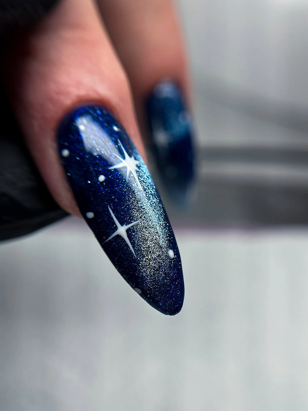 Dark navy glitter nail with one bright white starburst