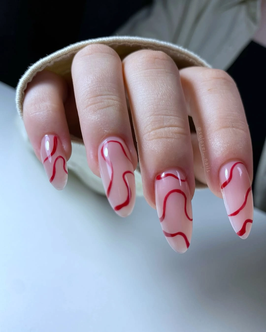 Sheer almond nails with red ribbon lines