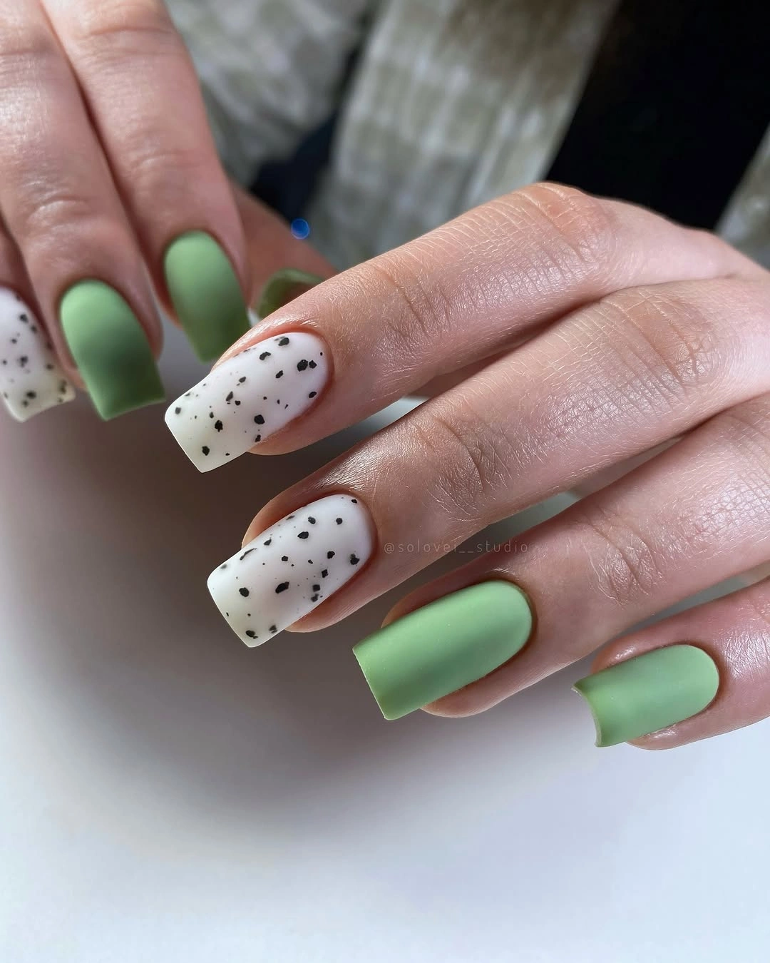 Sage green square nails with speckled accents