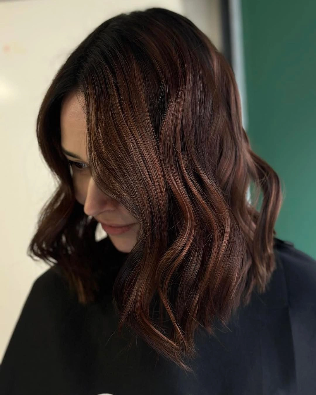 Shoulder-length dark brown waves with warm copper sheen