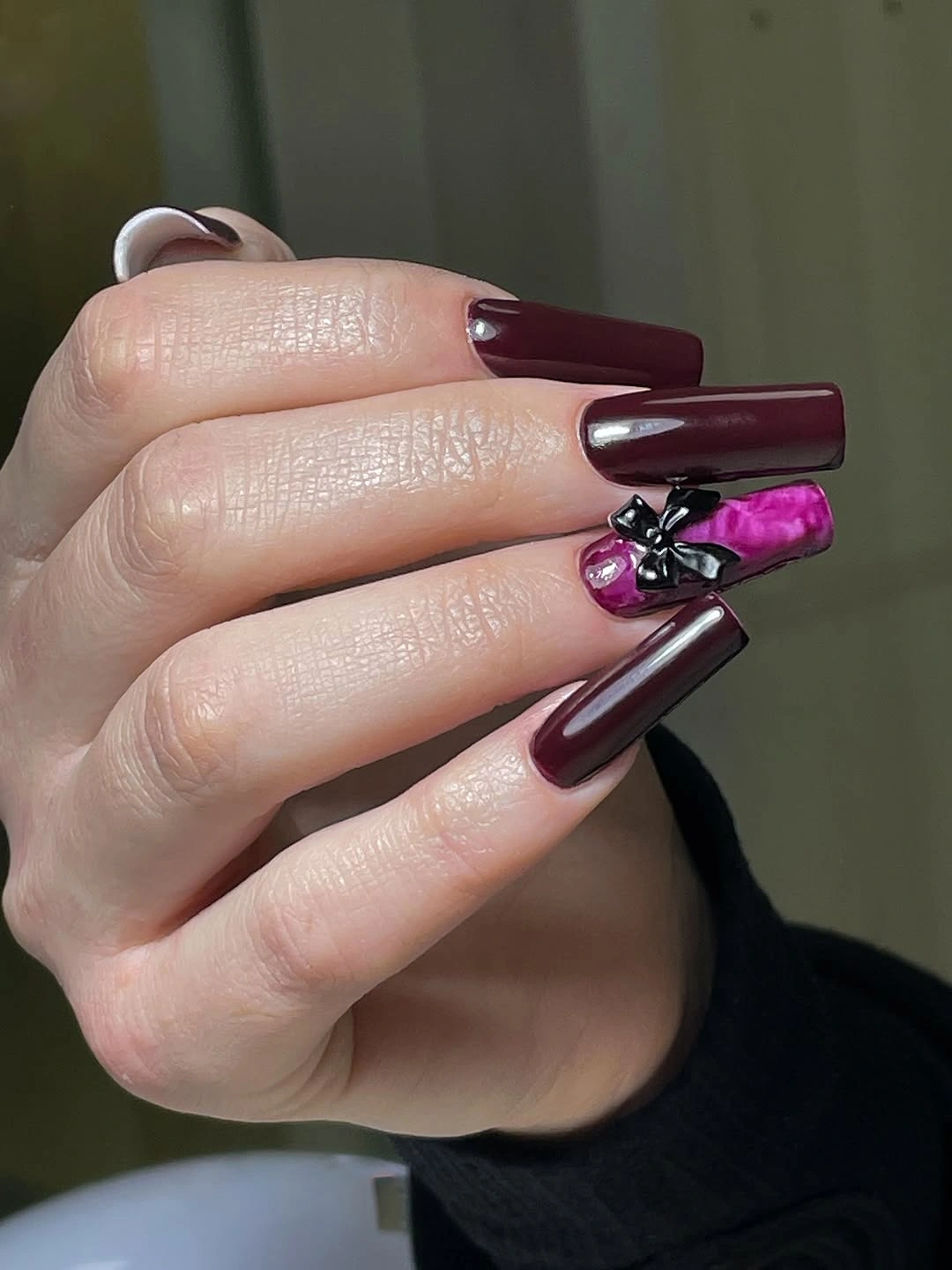 Long burgundy square nails with one ornate pink detailed accent