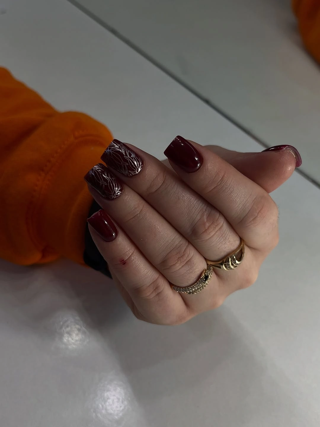 Short burgundy nails with one lighter ornate accent nail
