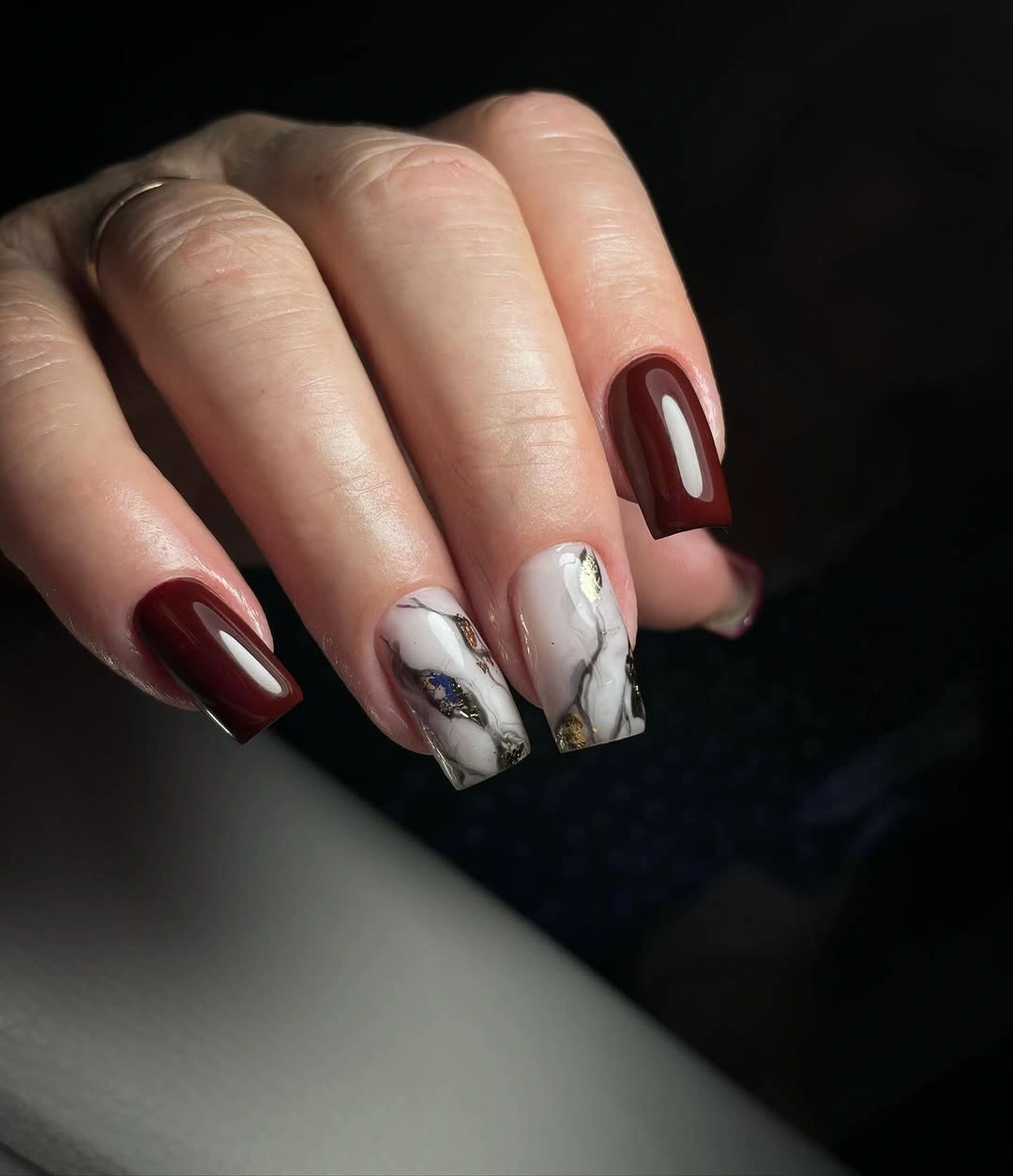 Medium burgundy nails with pale gray white marble accents