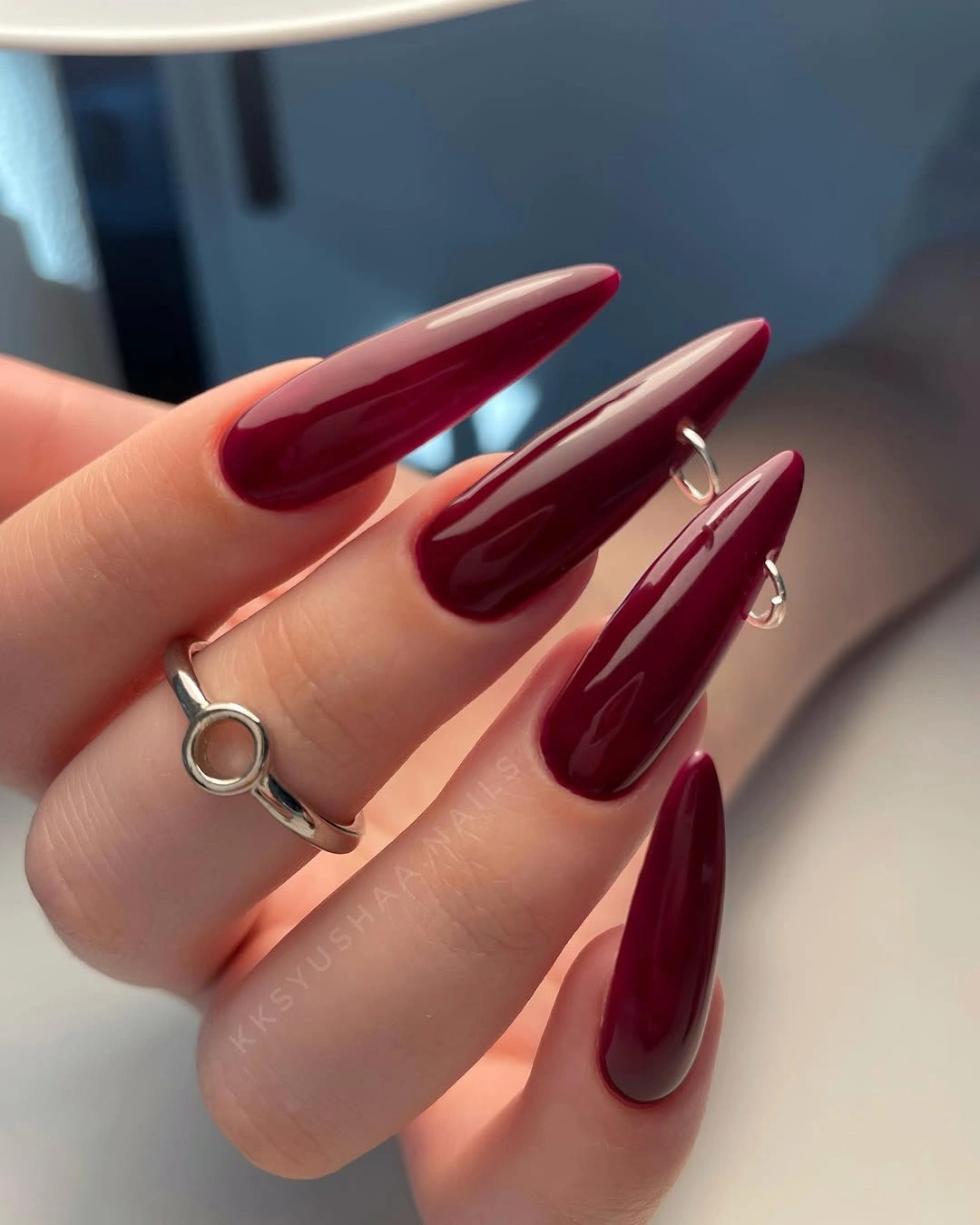 Long glossy burgundy almond nails in a solid deep wine shade