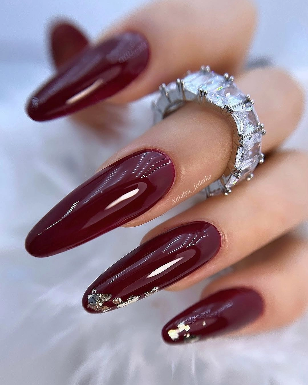 Long burgundy almond nails with sparse reflective tip accents