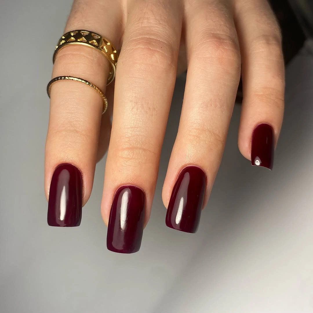 Short glossy burgundy square nails in a clean solid finish