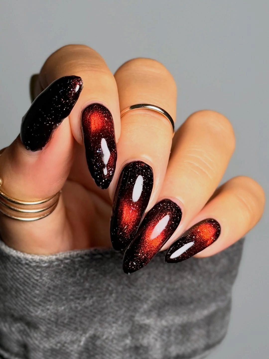 Burgundy black almond nails with elongated red reflective glow