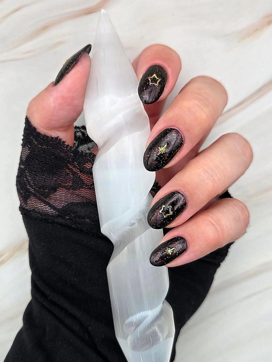 Black almond nails with subtle shimmer and tiny gold stars