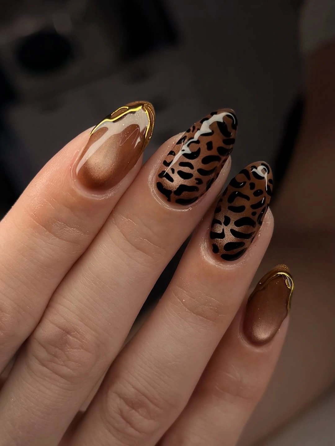 Brown almond nails with black spots and gold outlined accents