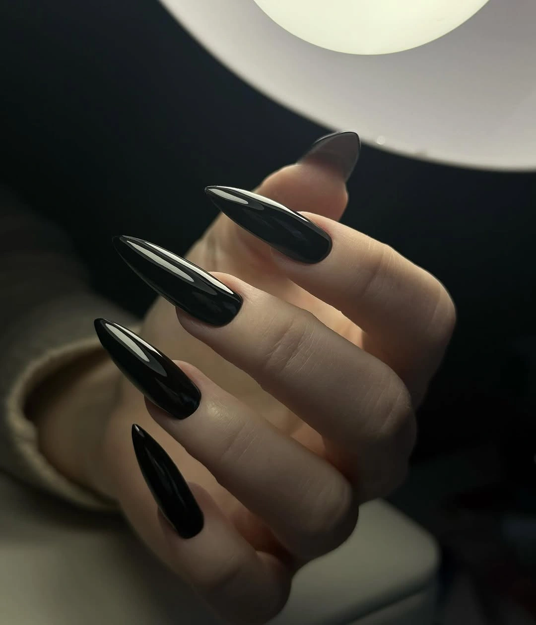 Glossy nearly black almond nails with clean reflective highlights