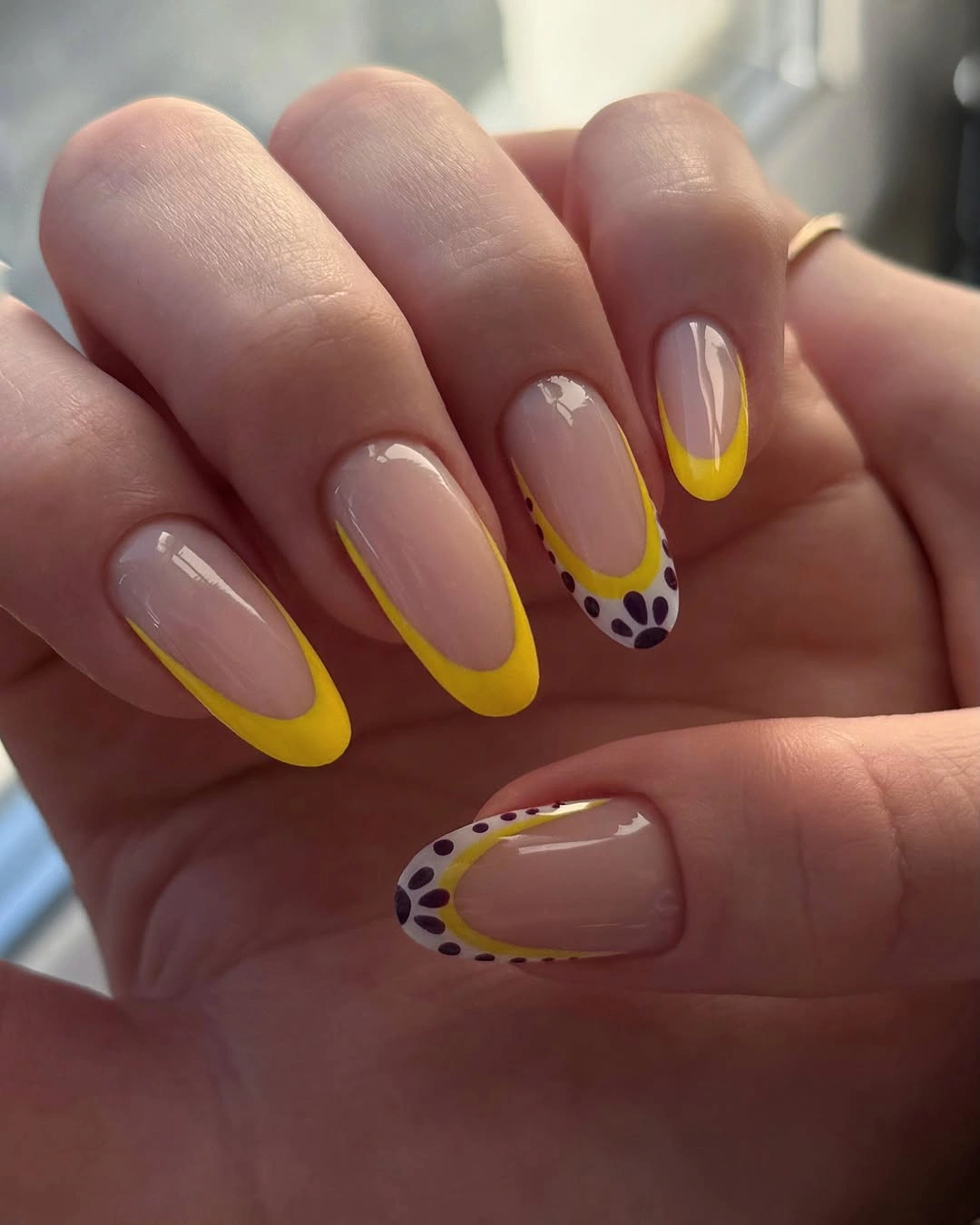 nude almond nails with yellow tips and spotted accent detail