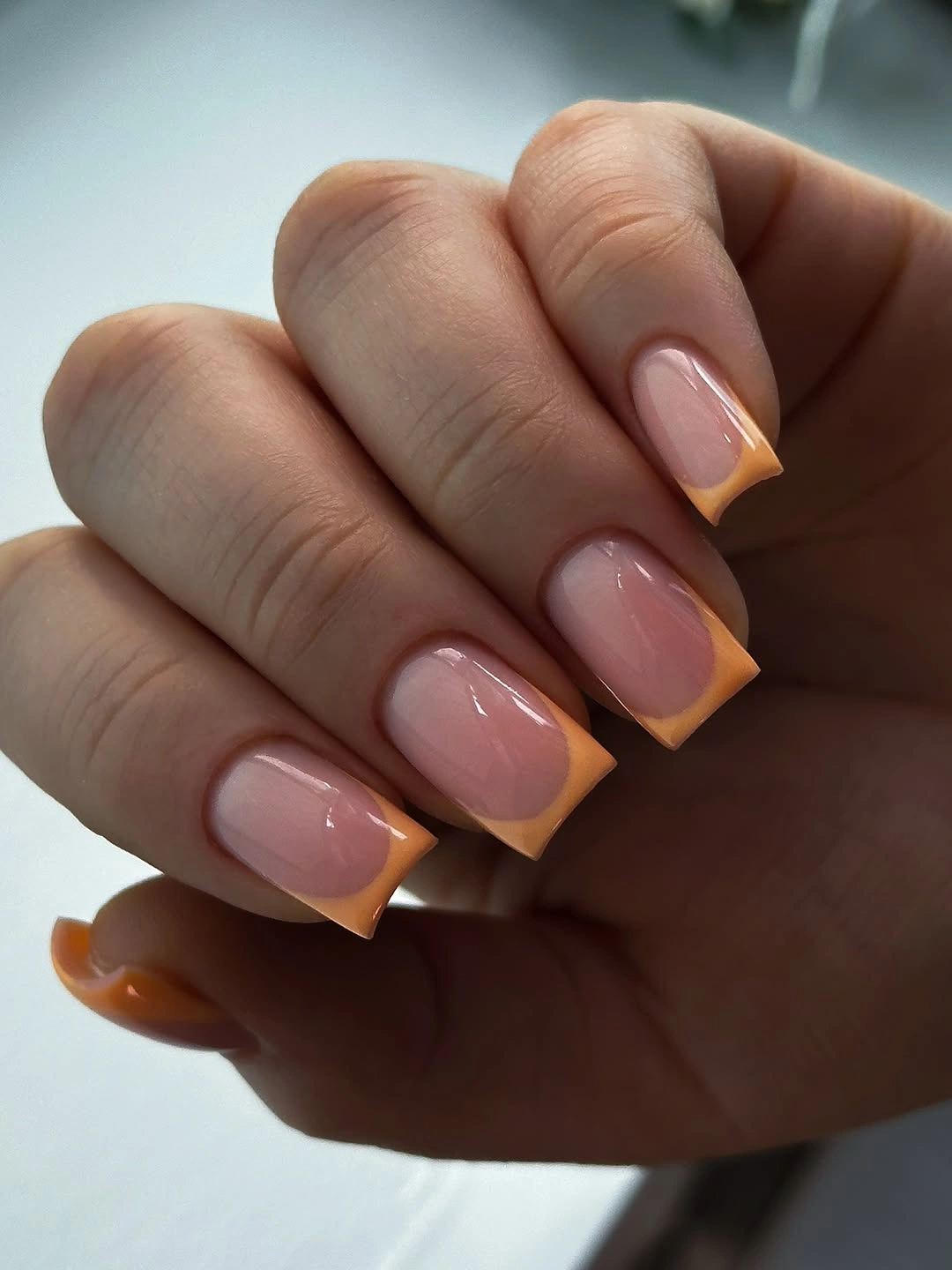 pink square nails finished with warm orange French tips