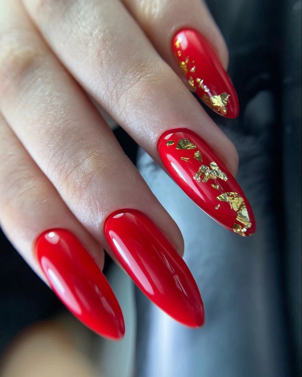 Long red almond nails with concentrated warm gold accents