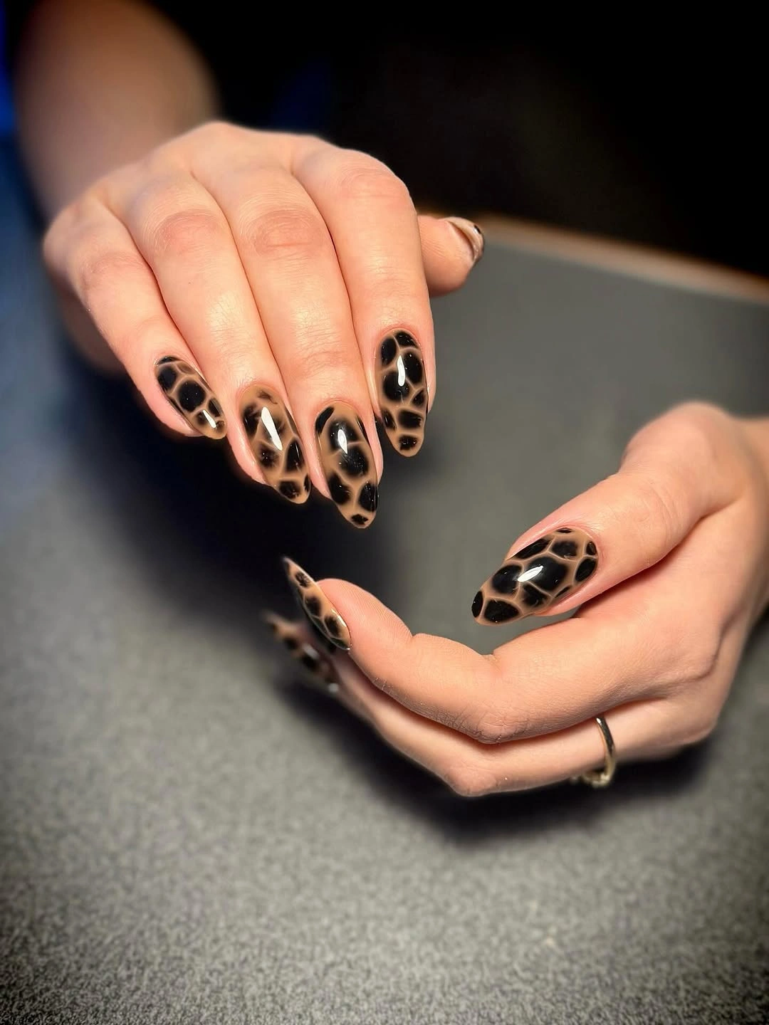 Medium almond nude nails with dense dark spotted pattern