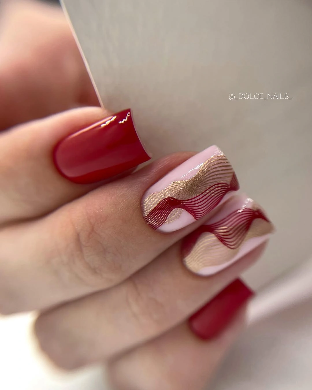 Medium red nails with nude wavy line-art accents