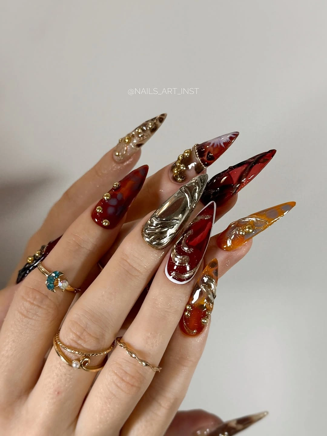 Ornate long nails with burgundy gold silver glitter and jewels