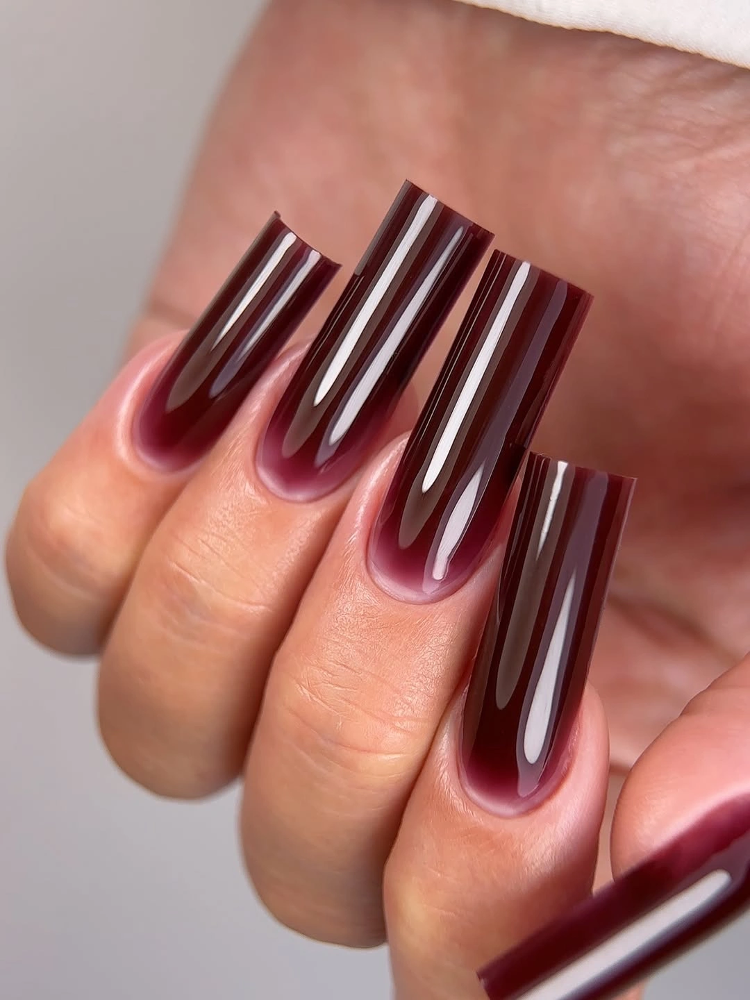 Long burgundy square nails with glossy tonal bands