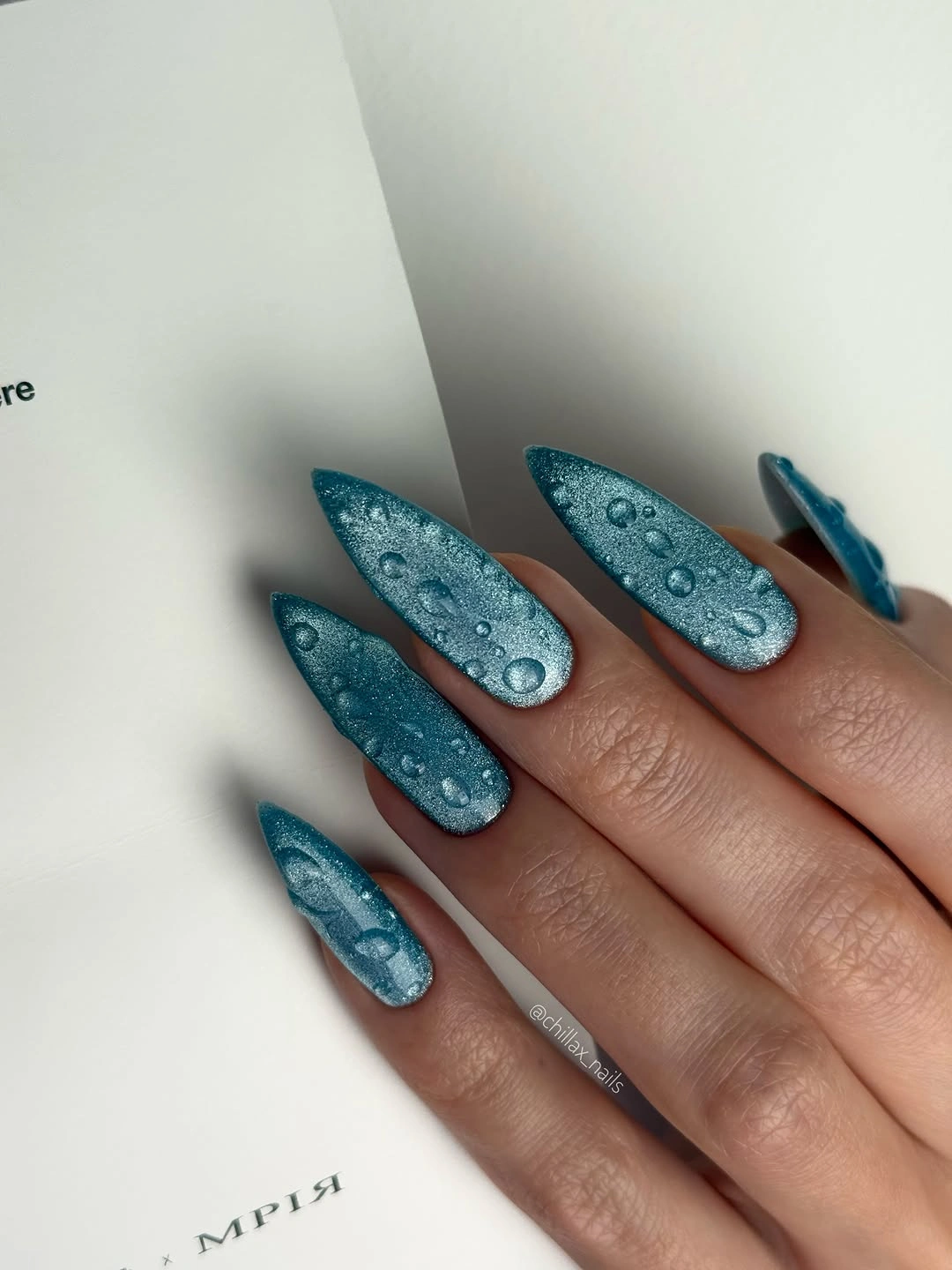 Long teal nails with reflective specks and raised droplets