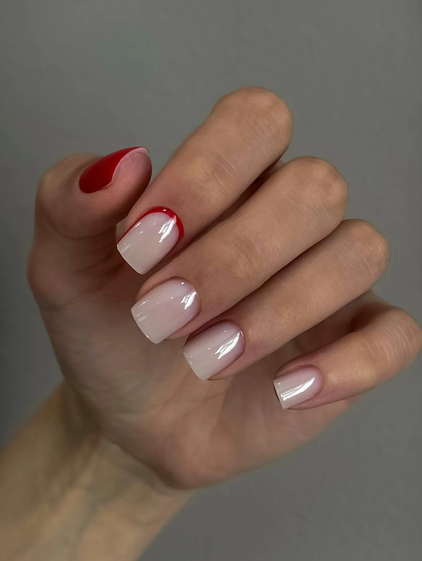 Milky short nails with one small red accent edge