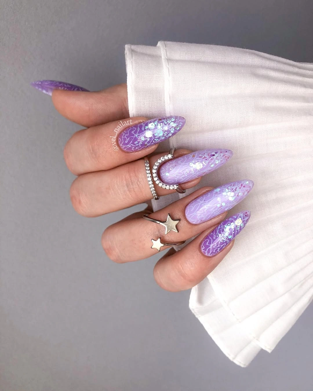 Lavender almond nails with pale linework glitter and stars