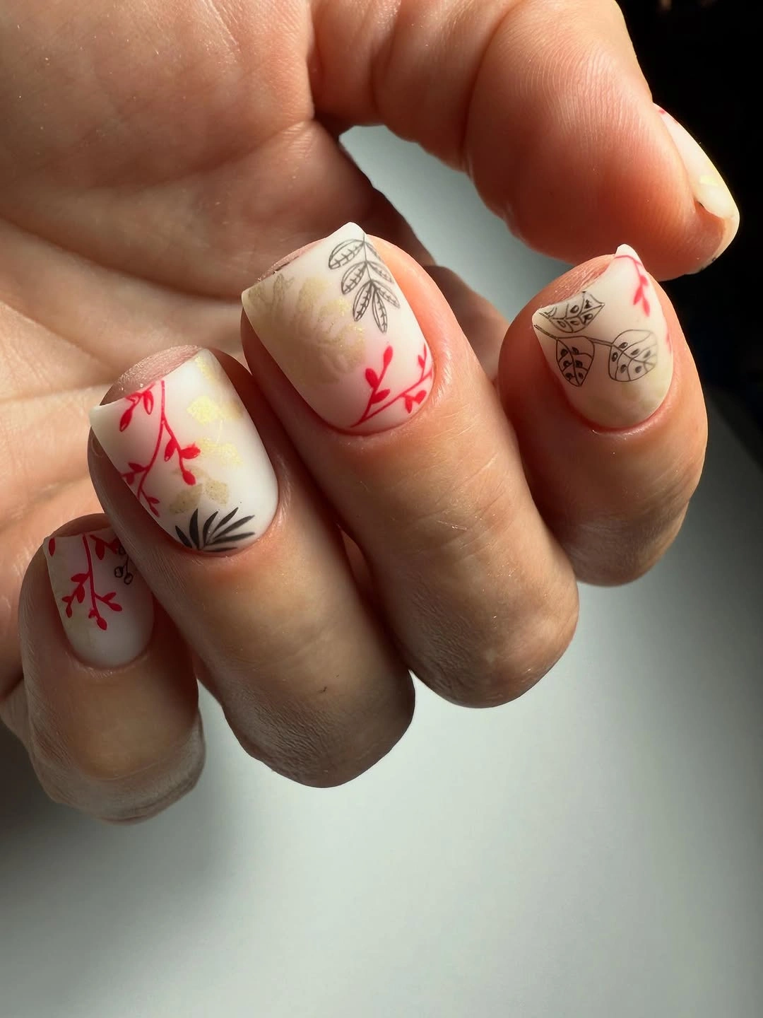 Cream rounded nails with fine red botanical accent lines